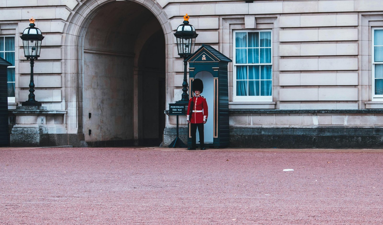 A guard in traditional red uniform stands at Buckingham Palace, London, United Kingdom.